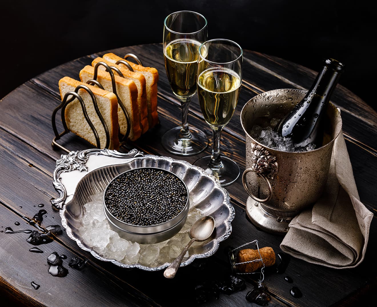 Sturgeon caviar in metal tin and Champagne on the wooden table. 