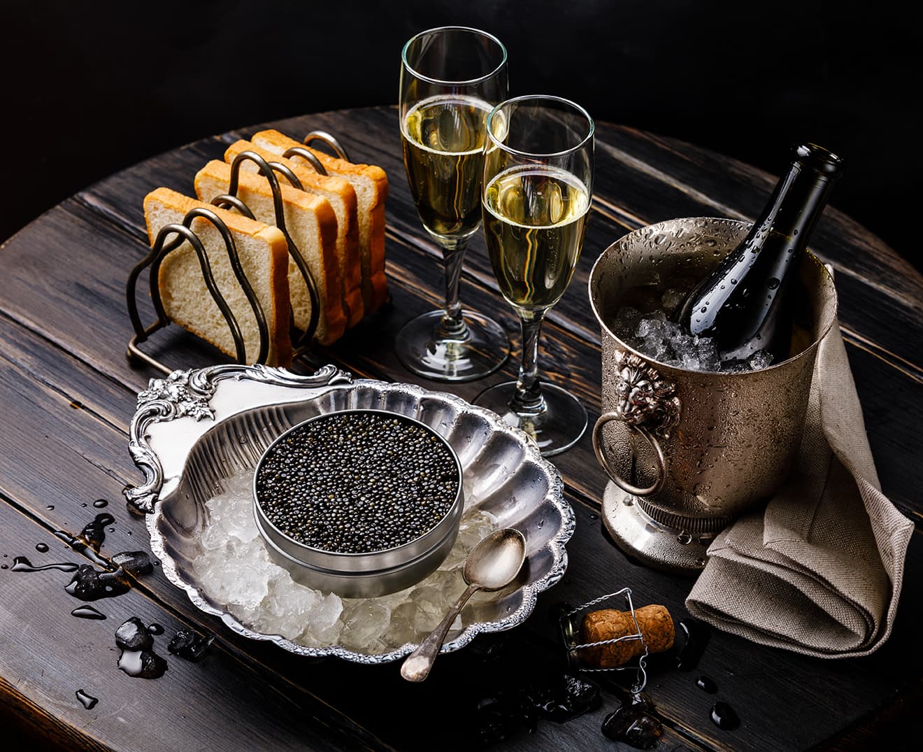 Sturgeon caviar in metal tin and Champagne on the wooden table.